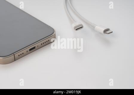 Apple iPhone 13 Pro und kabelgebundenes USB-C- oder Typ-C-Ladegerät. EU (Europäische Union) zwingt alle Geräte zur Verwendung von USB-C oder Typ-C. Stockfoto
