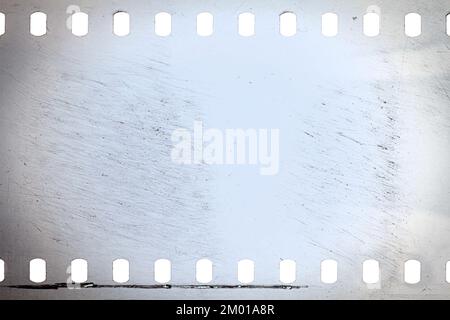 Staubige und schmutzige 35-mm-Filmtextur oder -Oberfläche. Perforierter, zerkratzter Kamerafilm isoliert auf weißem Hintergrund. Stockfoto