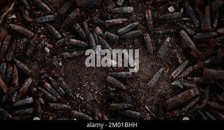 Verbrannte Munition, Kugeln und Hülsen nach dem Feuer. Verbranntes Waffenarsenal, Feuer in der Waffenkammer. Militärisches Thema Hintergrund. Militaristische Tapete Stockfoto