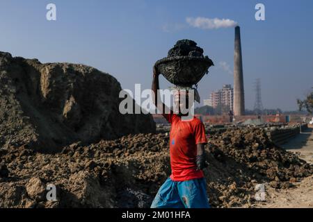 Dhaka, Dhaka, Bangladesch. 3.. Dezember 2022. Dr. Shahidul (30), der aufgrund von Elektrokurzschlüssen seine eine Hand verlor, arbeitet nun als saisonale Wanderarbeitnehmer auf einem Ziegelsteinplatz. Jedes Jahr arbeiten saisonale Wanderarbeitnehmer am 3. Dezember 2022 in einer ungesunden Umgebung auf dem Ziegelsteinfeld in Dhaka, Bangladesch. (Kreditbild: © Abu Sufian Jewel/ZUMA Press Wire) Stockfoto