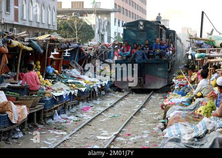 Dhaka, Dhaka, Bangladesch. 3.. Dezember 2022. Ein Pendlerzug fährt durch den Jurain Railgate Market in Dhaka. Die Händler verkaufen Obst und Gemüse nur wenige Zentimeter von der Zuglinie entfernt. (Bild: © Syed Mahabubul Kader/ZUMA Press Wire) Stockfoto