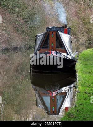 Narrowboat liegt im Winter vor Anker, und an einem sonnigen Tag im Winter erhebt sich Rauch aus dem Kamin am Staffordshire und Worcester Canal in Great Haywood. Stockfoto