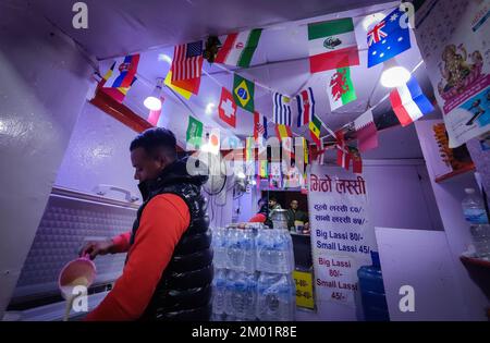 Kathmandu, Bagmati, Nepal. 3.. Dezember 2022. Ein Ladenbesitzer bereitet Buttermilch in lokaler Sprache in einem Laden zu, der am 3. Dezember 2022 in Kathmandu, Nepal, mit Flaggen der teilnehmenden Länder der FIFA-Weltmeisterschaft dekoriert ist. Auch die nepalesischen Fans zeigen nach dem Ende der Gruppenbühne und die K.o.-Runden der FIFA-Weltmeisterschaft 2022 beginnen am Samstag. (Kreditbild: © Sunil Sharma/ZUMA Press Wire) Kredit: ZUMA Press, Inc./Alamy Live News Stockfoto