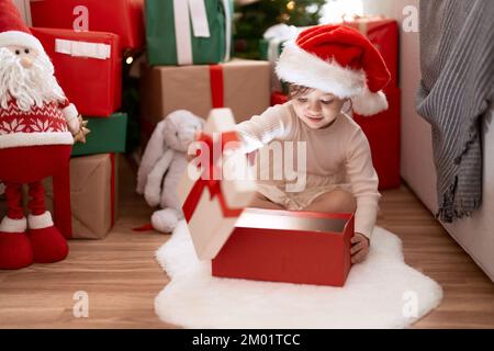 Ein entzückendes Mädchen, das zu Hause am weihnachtsbaum sitzt Stockfoto