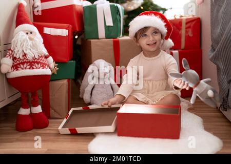 Ein entzückendes Mädchen, das zu Hause am weihnachtsbaum sitzt Stockfoto