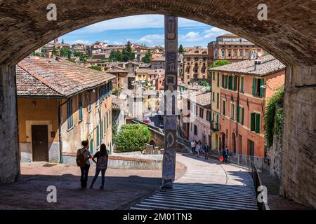 Zwei junge Menschen stehen unter der Brücke der Via Cesare Battisti, die zum mittelalterlichen Aquädukt (Via dell'Acquedotto) in Perugia, Umbrien, Italien führt Stockfoto