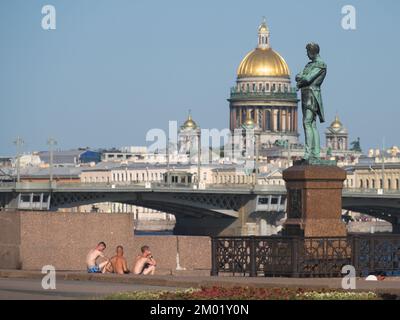 Sommerhitze in St. Petersburg, Russland: Junge Menschen sitzen am Denkmal von Ivan Krusenstern, nachdem sie im Fluss Newa gebadet haben Stockfoto