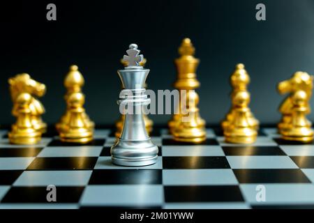 Silberkönig-Schachfigur steht einem anderen Gold-Team auf schwarzem Hintergrund gegenüber (Konzept für Führung, Problem oder Krisensituation) Stockfoto