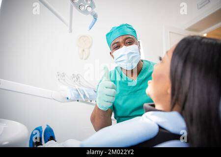 Ein zufriedener Zahnarzt während eines Besuchs mit einem Patienten macht die Daumen hoch Stockfoto