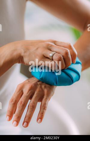 Eine Frau, die eine Eisbeutelkompression an einem schmerzhaften Handgelenk hält Stockfoto