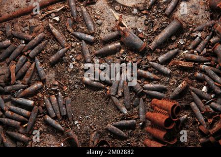 Verbrannte Munition, Kugeln und Hülsen nach dem Feuer. Verbranntes Waffenarsenal, Feuer in der Waffenkammer. Militärisches Thema Hintergrund. Militaristische Tapete Stockfoto