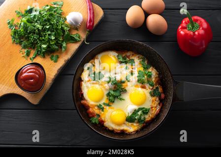 Zutaten für die Zubereitung von Shakshuka. Shakshuka in einer Eisenpfanne mit Zutaten. Traditionelles Gericht aus dem Nahen Osten. Spiegeleier mit Tomaten, Glocke Stockfoto