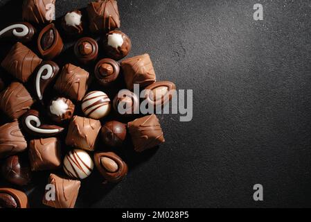 Schokoladenbonbons mit verschiedenen Füllungen, süßer Essenshintergrund. Kombiniere verschiedene Süßigkeiten. Schokolade mit verschiedenen Füllungen, süßes Essen Stockfoto