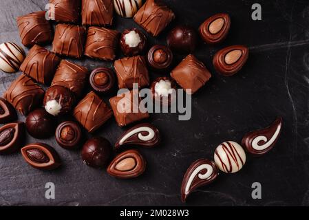 Schokoladenbonbons mit verschiedenen Füllungen, süßer Essenshintergrund. Kombiniere verschiedene Süßigkeiten. Schokolade mit verschiedenen Füllungen, süßes Essen Stockfoto