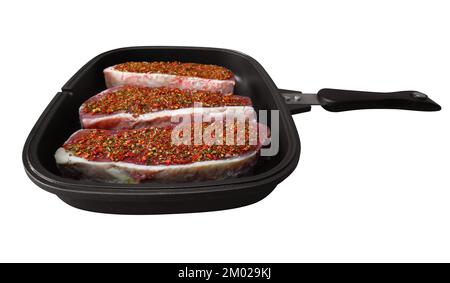 Rohe Rindersteaks mit Gewürzen in einem Topf. Isoliert auf weiß. Beschneidungspfad enthalten. Stockfoto