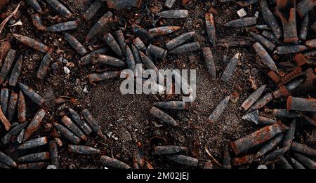 Verbrannte Munition, Kugeln und Hülsen nach dem Feuer. Verbranntes Waffenarsenal, Feuer in der Waffenkammer. Militärisches Thema Hintergrund. Militaristische Tapete Stockfoto