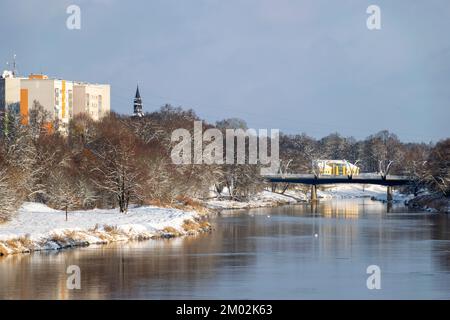 Winterlandschaft mit Fluss- und schneebedeckten Bäumen am Flussufer, Valmiera, Lettland Stockfoto