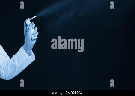 Beschnittenes Bild der weiblichen Hand mit Spray über schwarzem Hintergrund Stockfoto