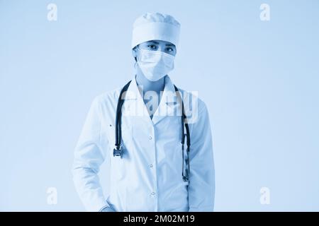 Portrait der jungen Ärztin trägt schützende medizinische Gesichtsmaske auf weißem Hintergrund, Kopierraum Stockfoto