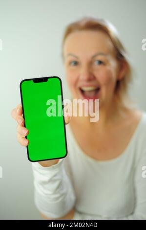 Gewinnen, um zu finden, was Freude Freude Freude Freude Freude Freude andere Emotionen Chroma Key Phone Grünes Bildschirmfeld für Werbung schöne Erwachsene glückliche Frau Stockfoto