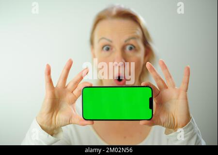 Gewinnen, um zu finden, was Freude Freude Freude Freude Freude Freude andere Emotionen Chroma Key Phone Grünes Bildschirmfeld für Werbung schöne Erwachsene glückliche Frau Stockfoto