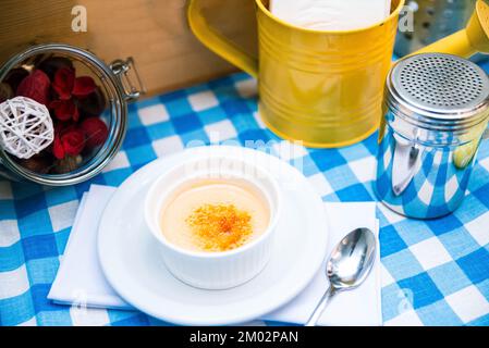 Eine Portion zarter Creme Brulee in Raminke auf dem Tisch auf einer karierten Serviette Stockfoto