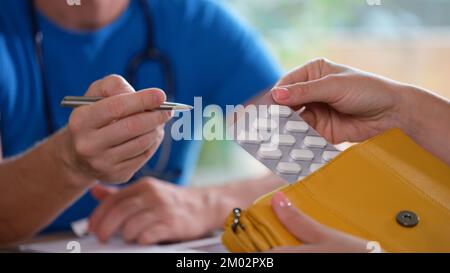 Männlicher Arzt verschreibt der Frau in seiner Klinik Pillen. Stockfoto