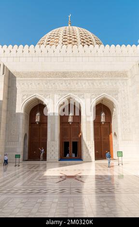 Muscat, Oman, Naher Osten - 10. Februar 2020: Bogengänge und geschnitzte Holztüren, die zur Sultan-Qaboos-Moschee führen. Stockfoto