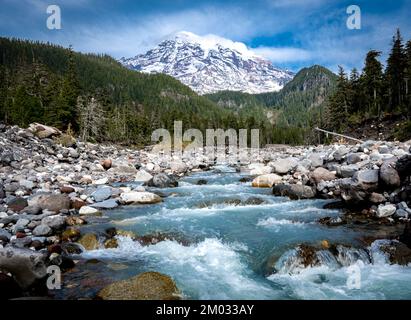 Blick auf den schneebedeckten Mount Rainier in der Nähe von Seattle mit blauem Himmel und Wolken auf dem Gipfel und dem Nisqually River Stockfoto