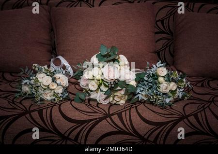 Zubehör für den Bräutigam. Schwarze Lederschuhe, Brautstrauß, schwarzer Ledergürtel auf braunem Hintergrund. Stockfoto