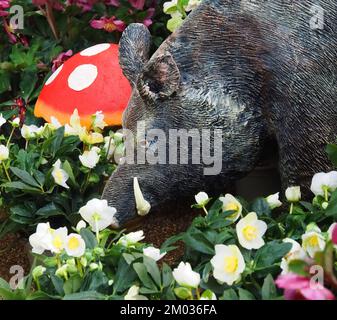 Skulptur eines Wildschweins in einem Garten mit Blumen Stockfoto