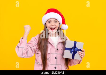 Glückliches Kind mit weihnachtsmann-Hut, hat Geschenkbox auf gelbem Hintergrund, Boxtag. Stockfoto