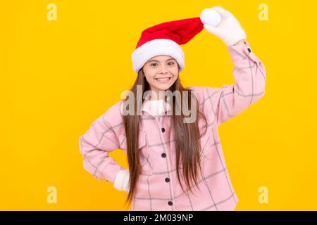 Wintermode. Frohes neues Jahr. Frohe Weihnachten. Ein glücklicher Junge mit weihnachtsmann-Hut. Teenager mit Fäustlingen auf gelbem Hintergrund. weihnachtsfeiertag. Kind trägt w Stockfoto