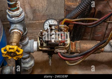 Druckschalter der Wasserpumpe und Rohrleitungen. Hausreparatur-, Wartungs- und Renovierungskonzept Stockfoto