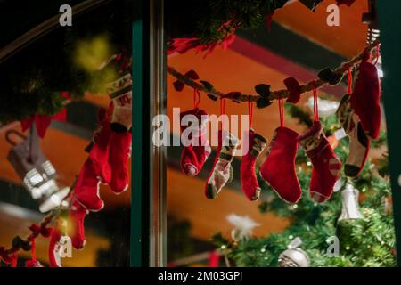 Gezielter Fokus auf das Aufhängen von Weihnachtssocken neben dem Schaufenster während der Weihnachtszeit. Stockfoto