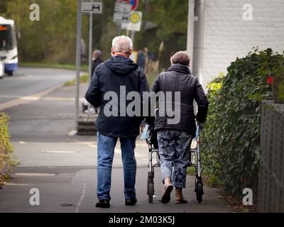 Bild eines älteren Ehepaars in Deutschland, das auf den Straßen von Aachen spaziert, die alte Frau, die einen Geher benutzt. Deutschland ist eines der am stärksten alternden Länder von E Stockfoto