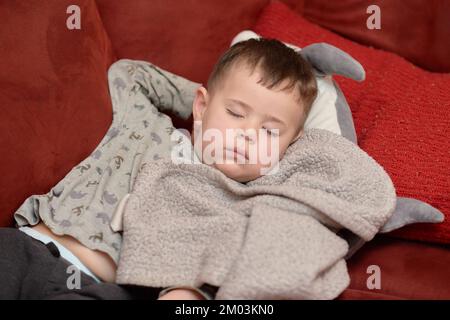 Süßer Junge, der nach dem Essen auf der Couch schläft Stockfoto
