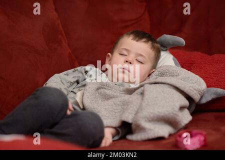 Süßer Junge, der nach dem Essen auf der Couch schläft Stockfoto