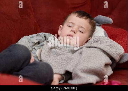 Süßer Junge, der nach dem Essen auf der Couch schläft Stockfoto