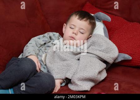 Süßer Junge, der nach dem Essen auf der Couch schläft Stockfoto