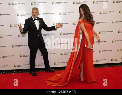 George Clooney kiddelt die Fotografen, nachdem sie den Zug auf seine Frau, Amal's Kleid, angepasst haben, während sie sich auf die Pose für Fotos vorbereiten, wenn sie am Samstag zum offiziellen Künstleressen ankommen, um die Empfänger der 45.. Jährlichen Kennedy Center Honors im Außenministerium von Washington, D.C. zu ehren. 3. Dezember 2022. Zu den 2022 Auszeichnungen zählen: Schauspieler und Filmemacher George Clooney, zeitgenössischer Christen und Pop-Sänger und Songwriter Amy Grant, legendärer Sänger von Soul, Gospel, R&B und Pop Gladys Knight, in Kuba geborene amerikanische Komponistin, Dirigentin und Pädagogen Tania León sowie die ikonische irische Rockband U2 Stockfoto