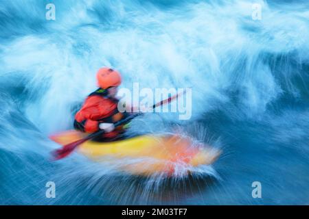 Wildwasser-Kajaktour durch eine stationäre Welle auf dem Bow River in Calgary, Alberta, Kanada. Unscharfe Bewegung. Stockfoto