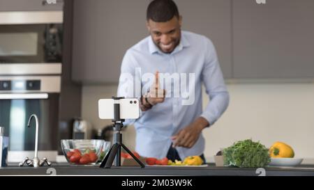 Fröhlicher afrikanischer Koch Blogger, der einen Video-Post für einen Blog aufnimmt Stockfoto