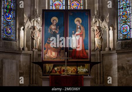 PRODUKTION - 30. November 2022, Sachsen-Anhalt, Naumburg: Bilder von St. Catherine (l) und St. Barbara by Lucas Cranach the Elder kann man auf dem Altar von Maria im Westchor der Kathedrale in Naumburg sehen. Der Leipziger Maler Michael Triegel hatte das 1519 von Lukas Cranach dem Ältesten geschaffene Kirchengemälde fertiggestellt. Die Lage des Altarstücks im Westchor zwischen den berühmten Spenderfiguren ist umstritten. Nach Ansicht von Experten des Icomos World Council on Monuments beeinträchtigt das Kunstwerk die „extrem sensiblen visuellen Beziehungen im Westchor“. Wegen seiner Lage, t Stockfoto