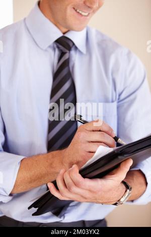 Schreiben Sie alle wichtigen Punkte auf. Ein Geschäftsmann, der sich Notizen macht. Stockfoto