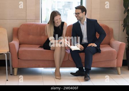 Zwei glückliche männliche weibliche Kollegen erzählen Witze, lachen und kommunizieren gern Stockfoto