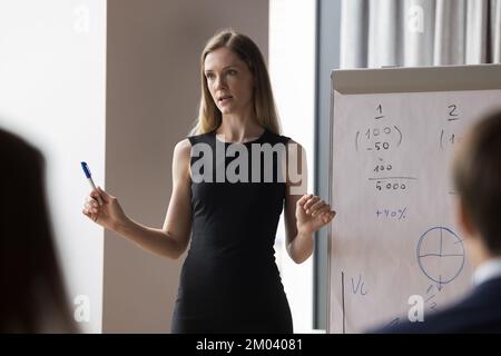 Junge Businesstrainerin hält die Präsentation auf einem Flipchart Stockfoto