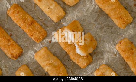 Knusprige panierte Fischstäbchen aus wild gefangenem Alaska-Pollock aus der Nähe auf einer Backpfanne, direkt aus dem Ofen, flach liegend Stockfoto