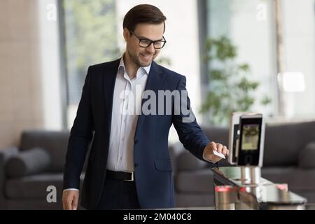 Ein Geschäftsmann zieht die Karte in den elektronischen Leser und öffnet automatische Tore Stockfoto