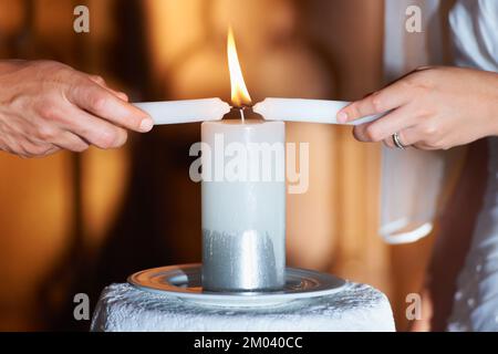 Eine ewige Flamme... kurze Nahaufnahme von ein paar Kerzen während ihrer Hochzeitszeremonie anzünden. Stockfoto